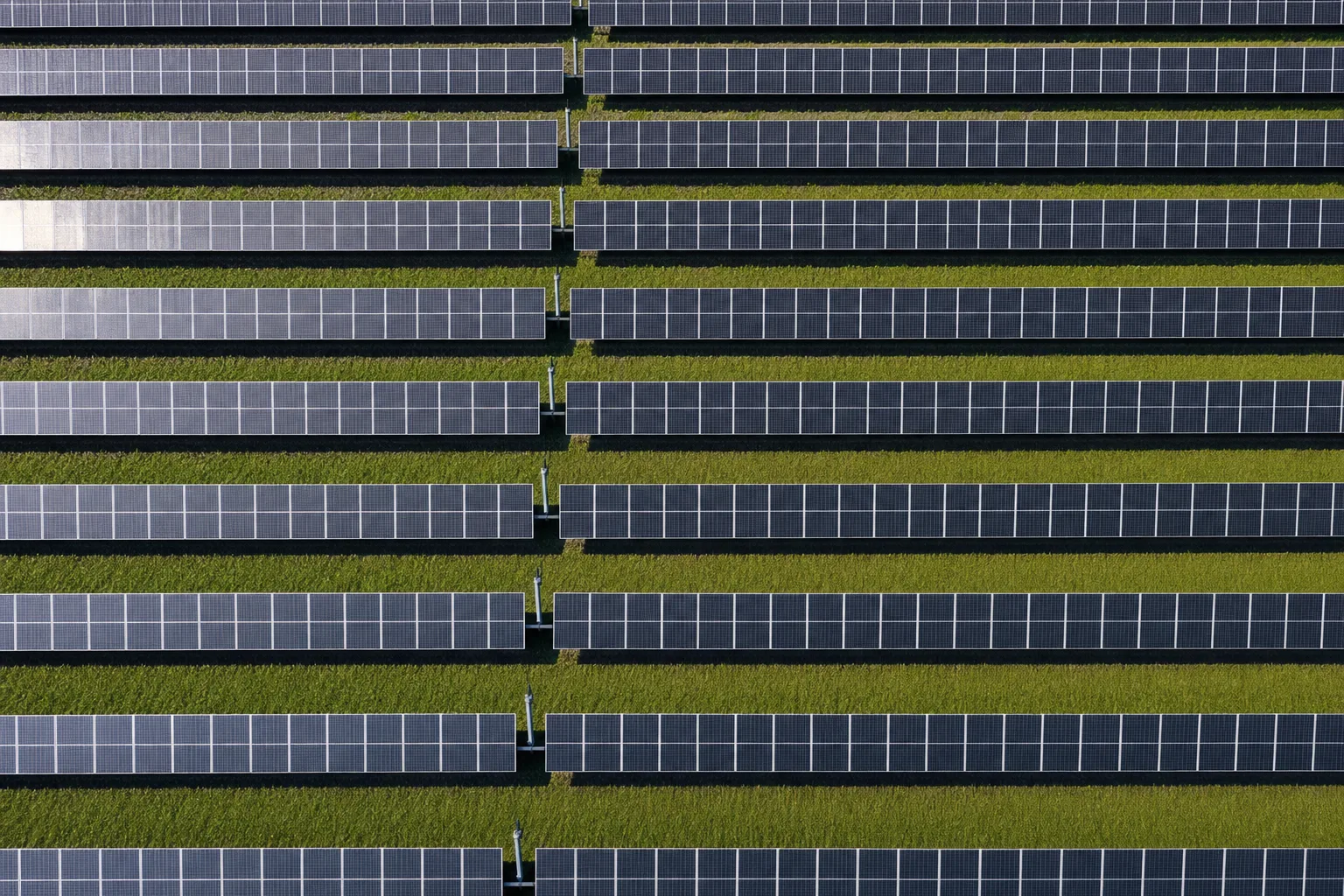 Aerial view directly above rows of solar panels forming a geometric grid pattern